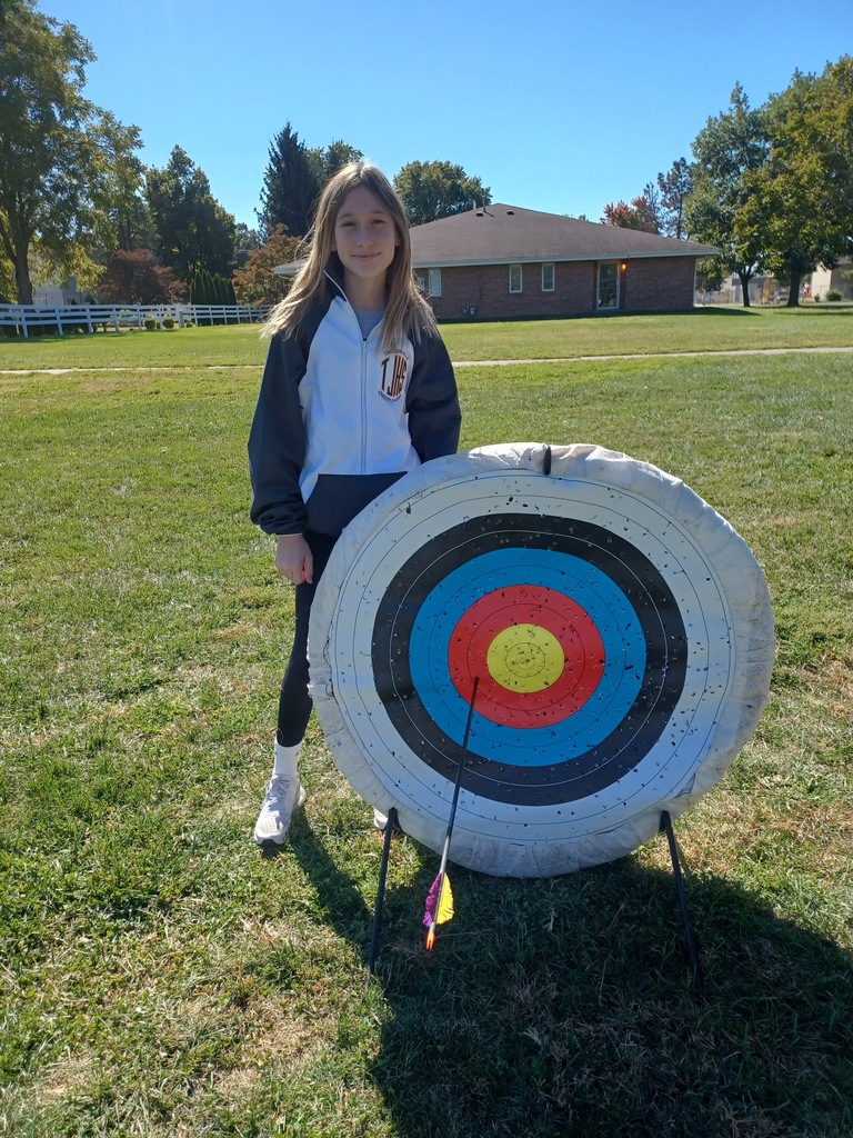 Student standing by archery target