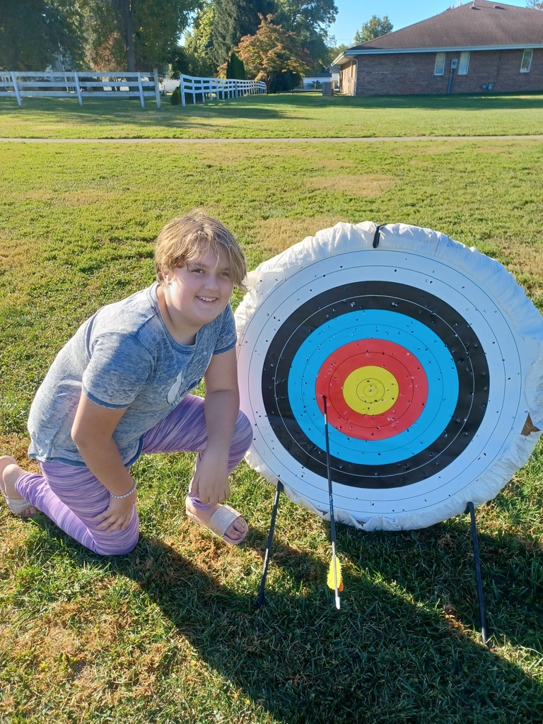 Student standing by archery target